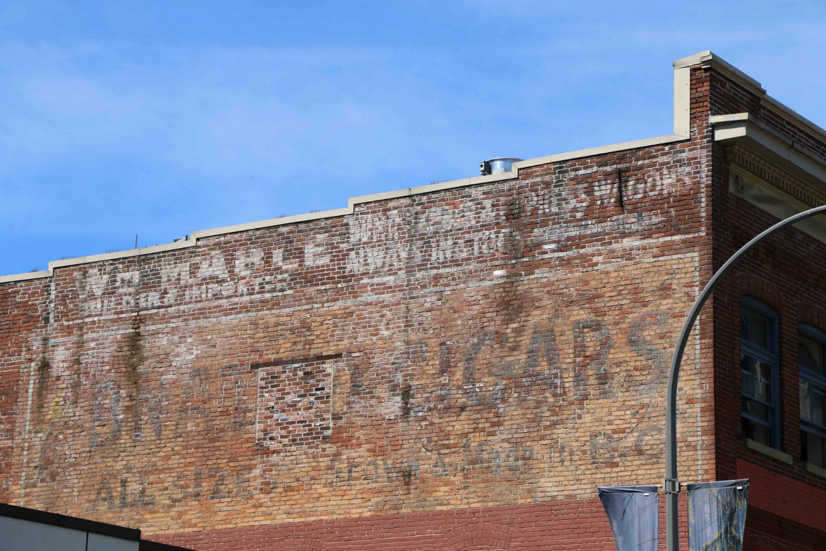 The east wall of 713-715 Johnson Street still shows the early 20th century painted signs for Mable Carriage Works and other businesses which operated in this building.